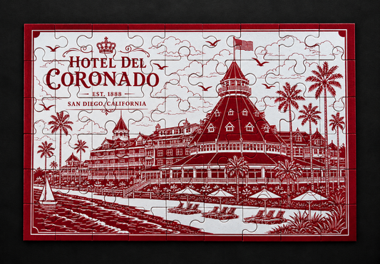 Assembled red Hotel del Coronado metal jigsaw puzzle with white etched artwork of the hotel and beachfront, viewed from above.