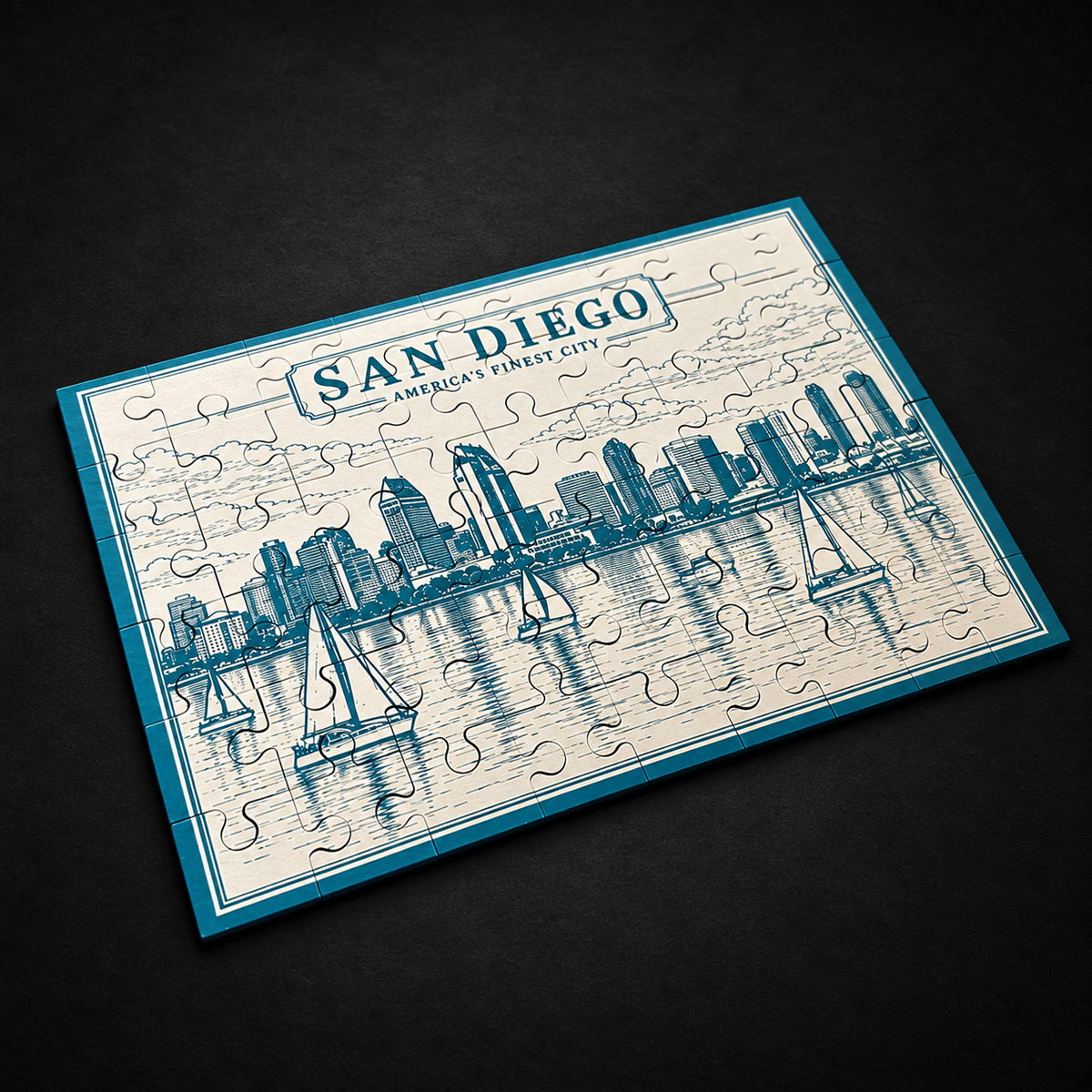 Light blue San Diego skyline metal jigsaw puzzle with sailboats and waterfront buildings, lying flat at an angle on a dark surface.