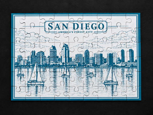 Light blue San Diego skyline metal jigsaw puzzle with etched waterfront buildings and sailboats, viewed from above on a dark background.